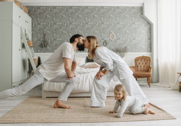 A family enjoying playful bonding moments in a stylish, minimalistic bedroom setting.